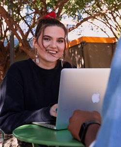 A woman smiling while checking her social media on a laptop image